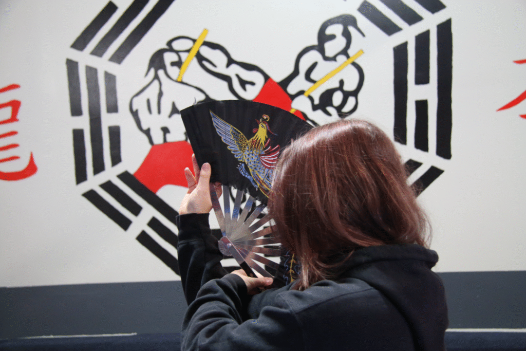 Masha Kyselova practices the precise movements of her fan form. Between open-hand forms, individual weapons, and defense techniques, she had years' worth of material to drill and refine leading up to her much-anticipated black belt test. "All of kung fu is based off of muscle memory," Kyselova said.