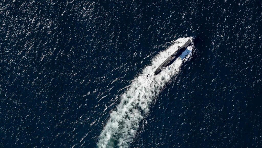 Real Underwater World Events Underline RN Atlantic Bastion Underwater Warfare Requirement A NATO submarine sails on the surface during the Alliance’s ‘Dynamic Mongoose’ ASW exercise in the North Atlantic in May 2026. The UK’s ‘Atlantic Bastion’ underwater sensing construct will help the RN and NATO navies deter and defend against Russia’s growing underwater threat. (Image: Crown copyright/UK Ministry of Defence)